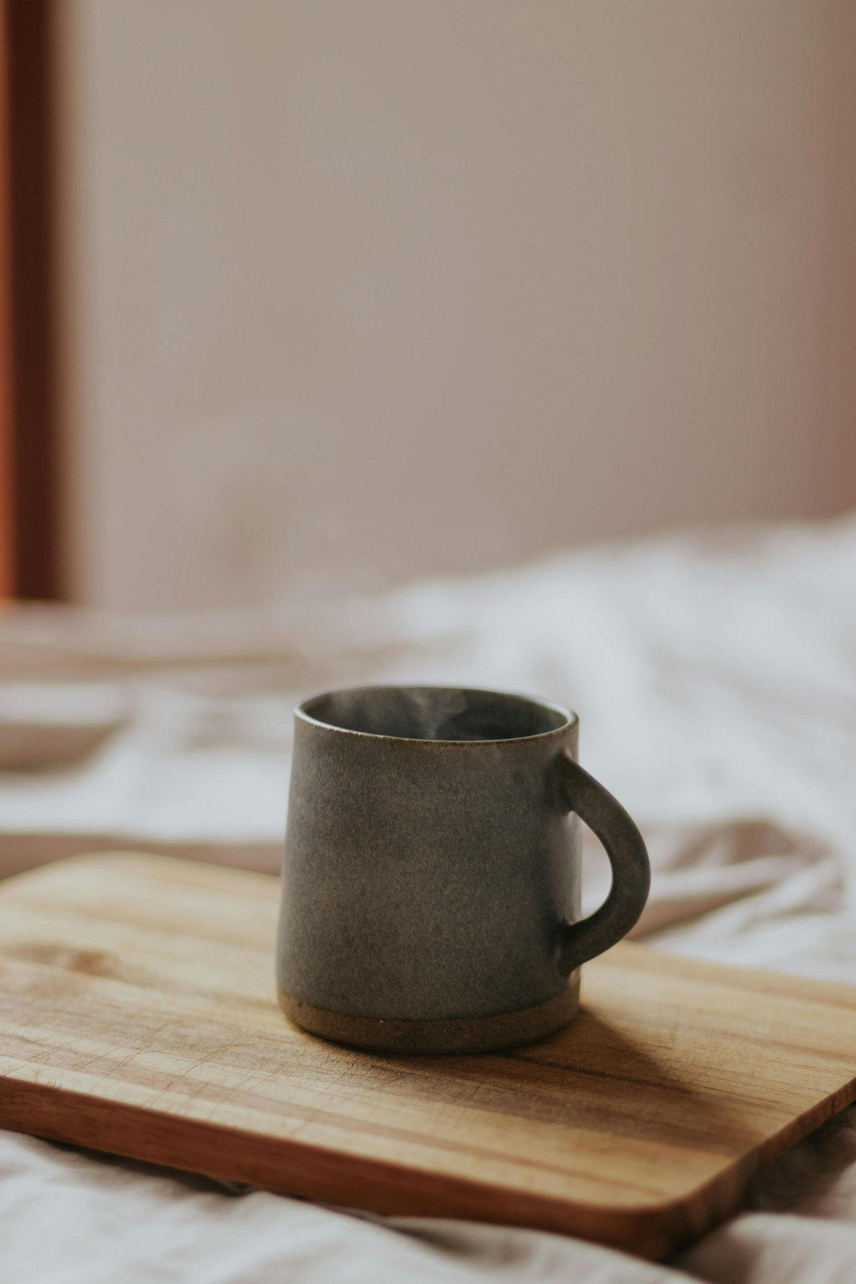 Een kopje dampende thee op een houten plankje op de tafel